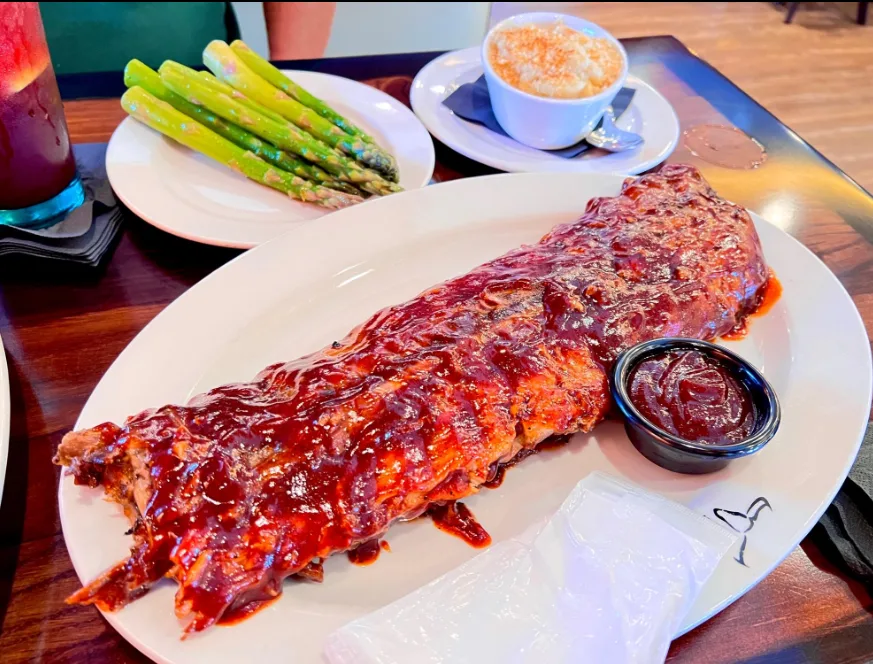 A full rack of glazed baby back ribs with asparagus and mac and cheese
