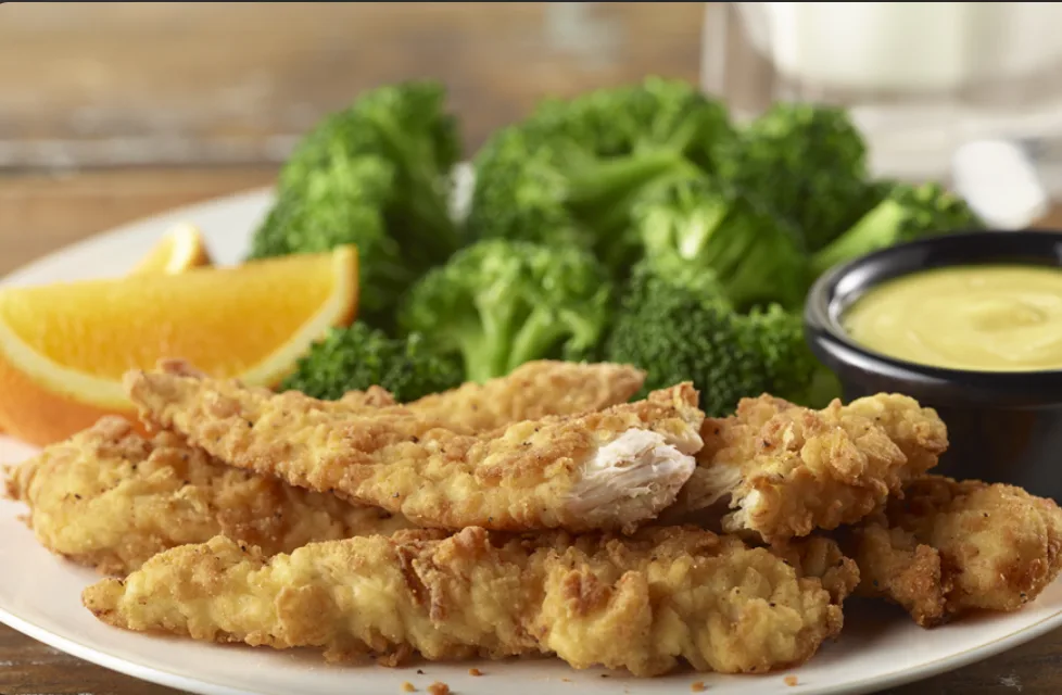 Crispy fried chicken tenders served with broccoli, an orange slice and dipping sauce (illustrative image)
