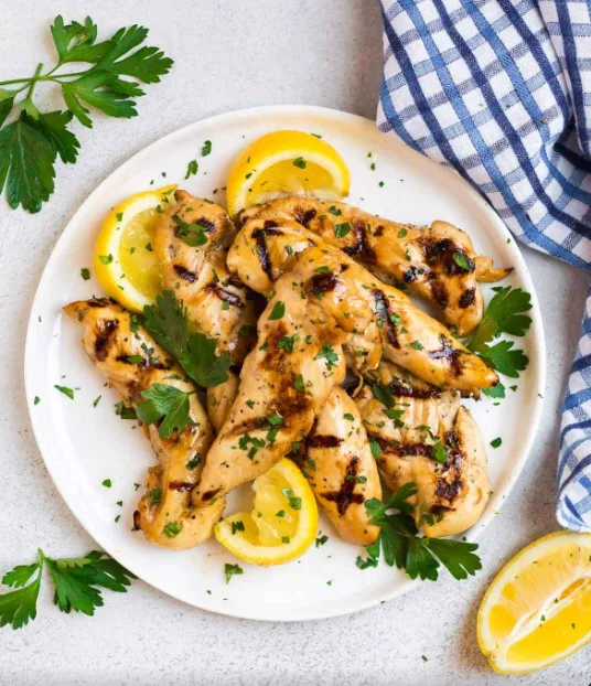 Grilled chicken tenders garnished with parsley and lemon wedges (illustrative image)