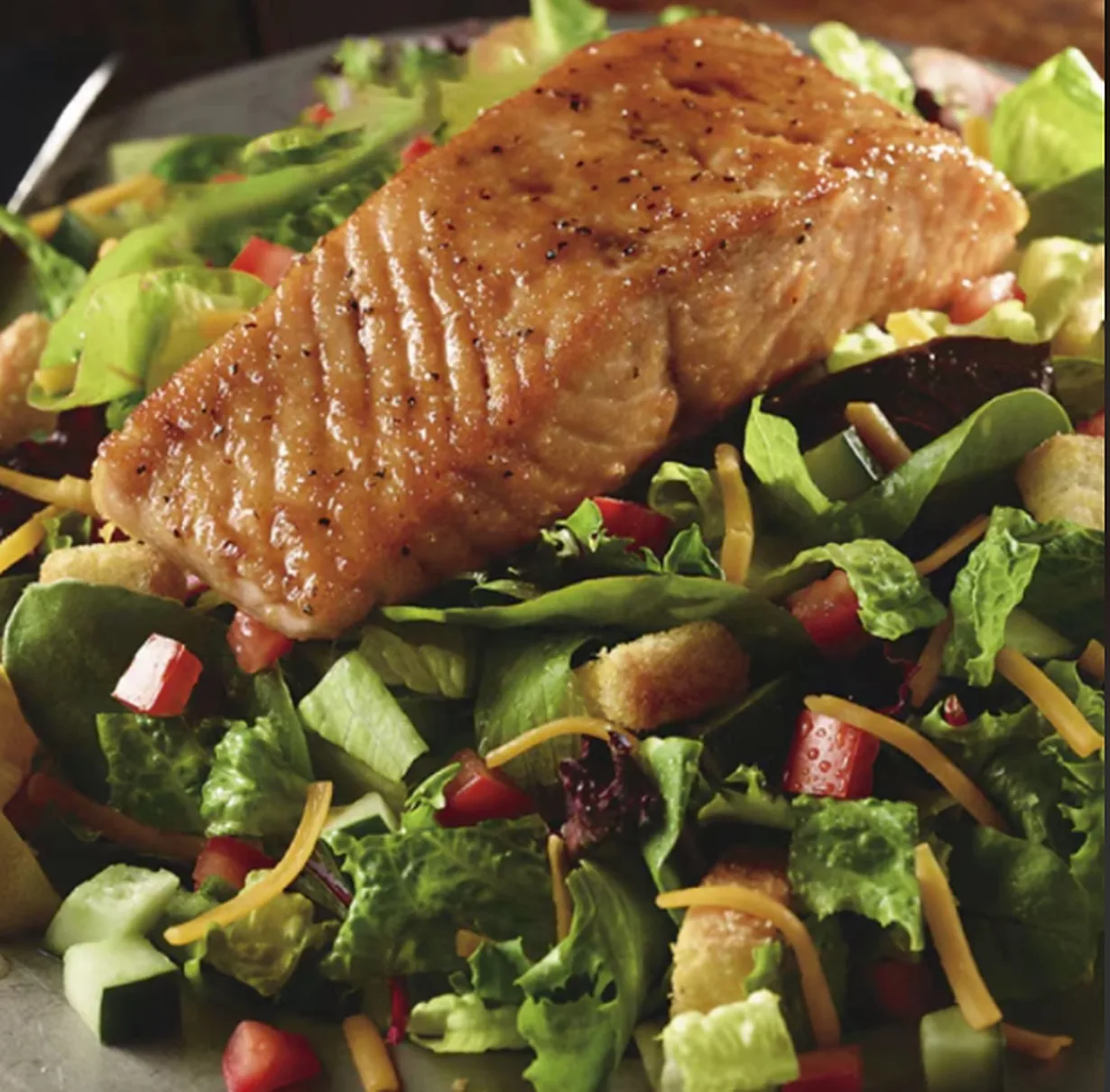 Field greens salad topped with grilled salmon (illustrative image)