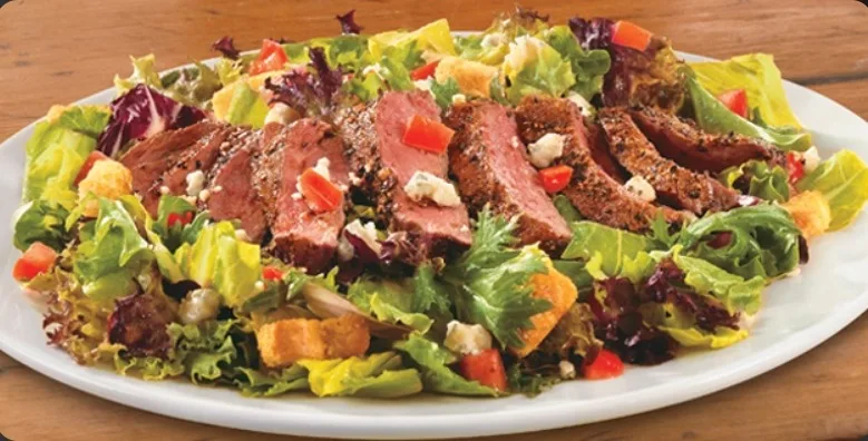 Sliced peppered sirloin over mixed greens, a lighter lunch plate (illustrative image)