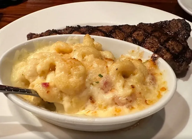 Baked mac and cheese served with a grilled steak (illustrative image)